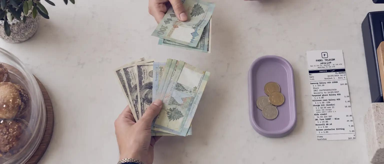 Dollars and lira changing hands over a marble counter, beside the printed receipt.
