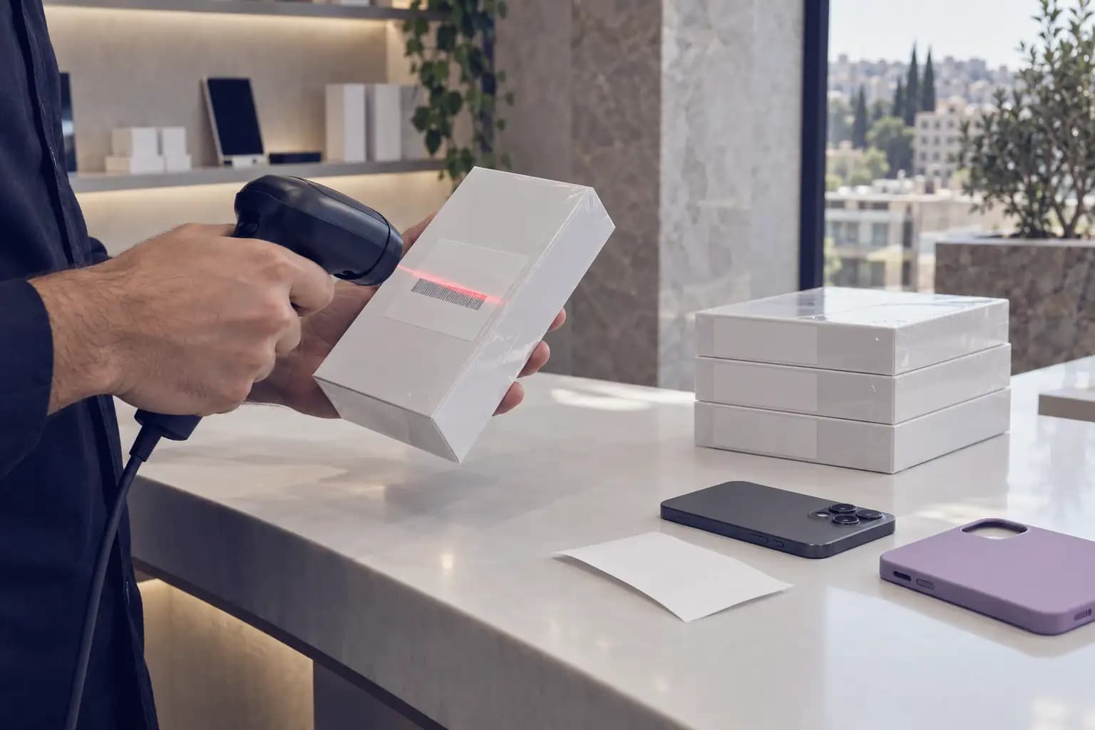 At a phone shop counter, a new phone’s box is scanned; its IMEI goes straight into stock.